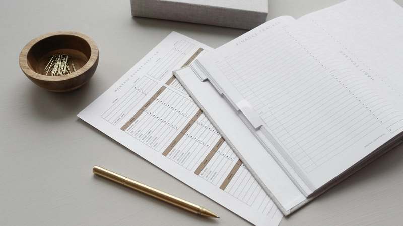 Person reviewing a detailed zero-based budget spreadsheet on a laptop with coffee and notebook nearby
