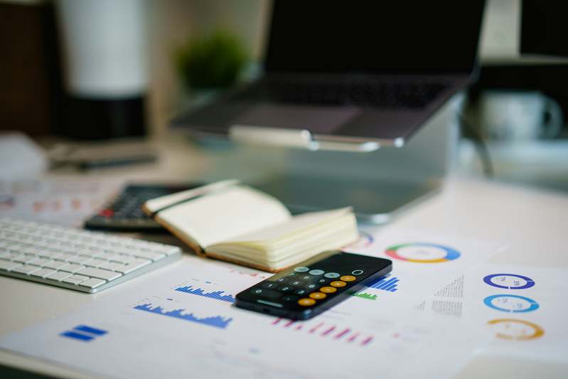 Two hands holding a notebook open to a zero-based budget plan with pen and calculator